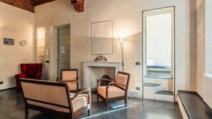 A living room with a fireplace, a red chair, and a sofa. - Appartamento della Zecca - Affitti Brevi Italia (Lucca)