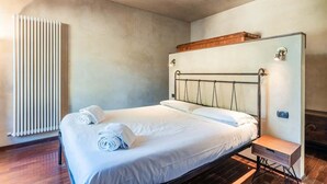 A neatly made bed with a wooden headboard, a bedside table, and a wall-mounted light fixture. - Appartamento della Zecca - Affitti Brevi Italia (Lucca)