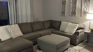 A modern living room with a sectional sofa, a small ottoman, and decorative wall art. - River house with scenic view (Bullhead City)