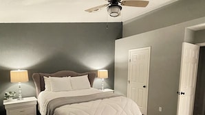 A bedroom with a bed, nightstands, a ceiling fan, and a door. - River house with scenic view (Bullhead City)
