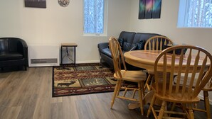 A living room with a dining area, featuring a fireplace, a sofa, a coffee table, and a rug.