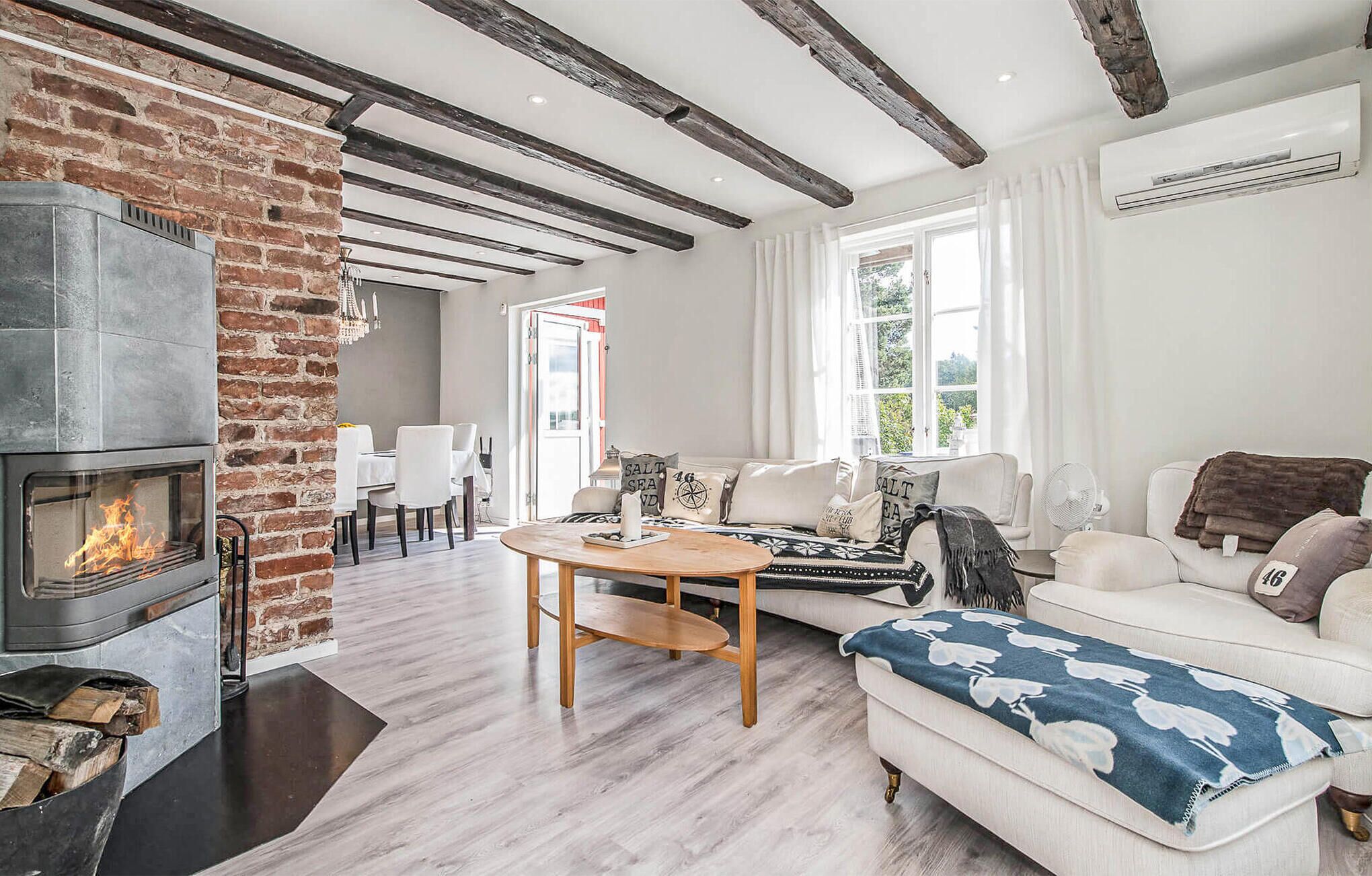 A living room with a fireplace, a sofa, a coffee table, and a dining area with chairs.