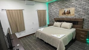 Une chambre à coucher avec un lit, une télévision, un bureau et un mur décoré d’un motif en briques.
