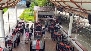 Un restaurant en plein air doté de nombreuses tables et chaises, d’un toit abrité et offrant une vue sur un jardin.