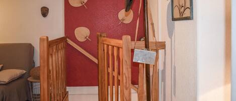 Una scala di legno con una parete rossa e una porta bianca. Si vedono tre ventilatori appesi al muro.