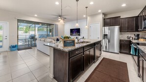 A modern kitchen with dark cabinetry, stainless steel appliances, and a central island.