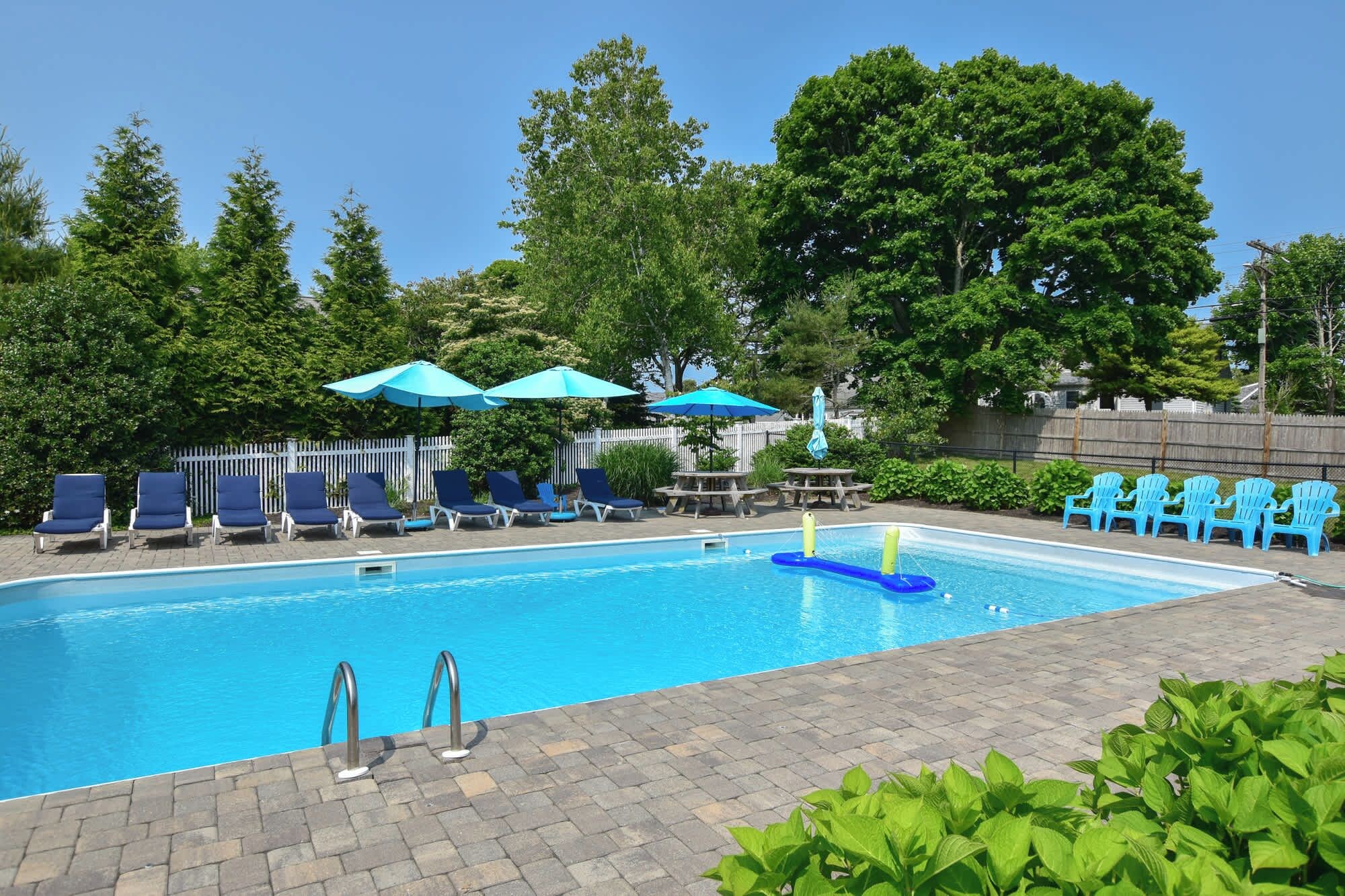 A swimming pool with lounge chairs and umbrellas, surrounded by greenery.