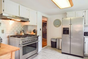 Una cocina con armarios blancos, una estufa de acero inoxidable y un refrigerador.