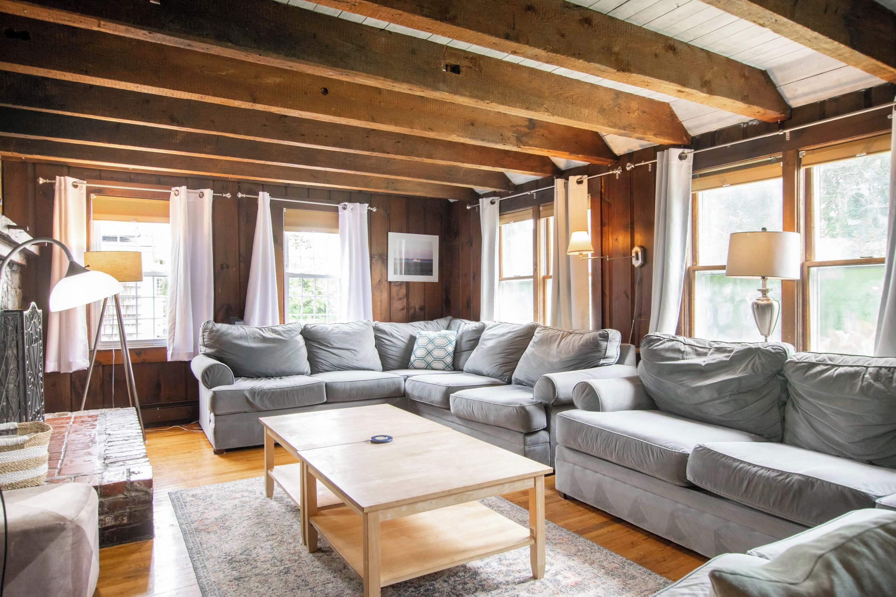 A cozy living room with a sectional sofa, a wooden coffee table, and a television mounted on the wall.