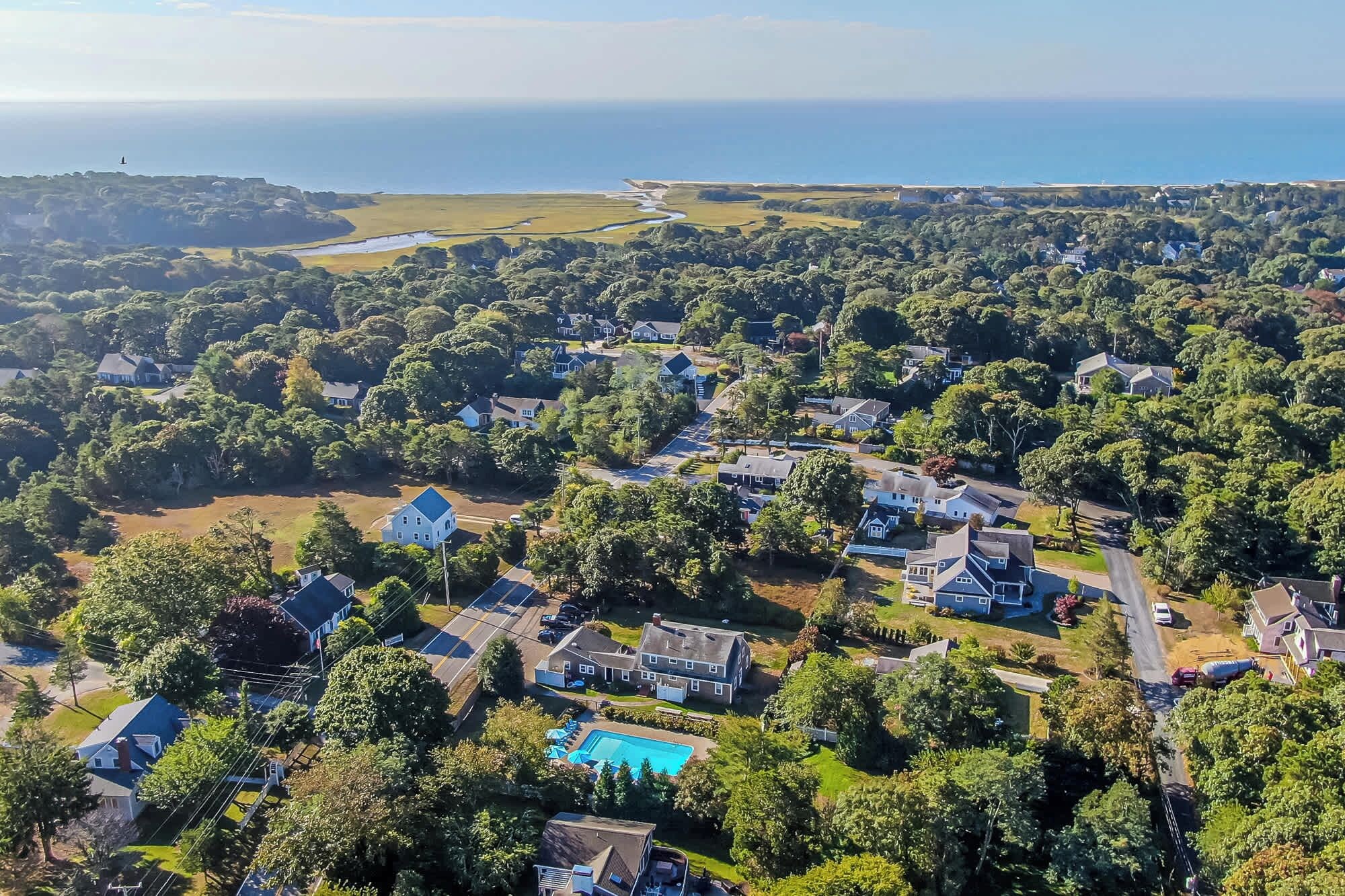 Vista aérea de una zona residencial con casas, piscina y vista al océano.