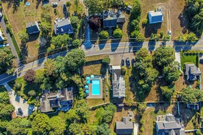 An aerial view of a residential area with multiple houses, a swimming pool, and a road.
