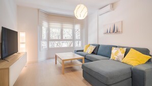 Una sala de estar moderna con un sofá gris, una mesa de centro de madera y un televisor de pantalla plana sobre un mueble de madera.