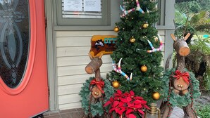 A decorated Christmas tree with ornaments and lights, a wooden sign with 'OFF' and 'AROUND' text, and two reindeer figures with garlands. - Nature Coast Inn and Cottages (Inglis)