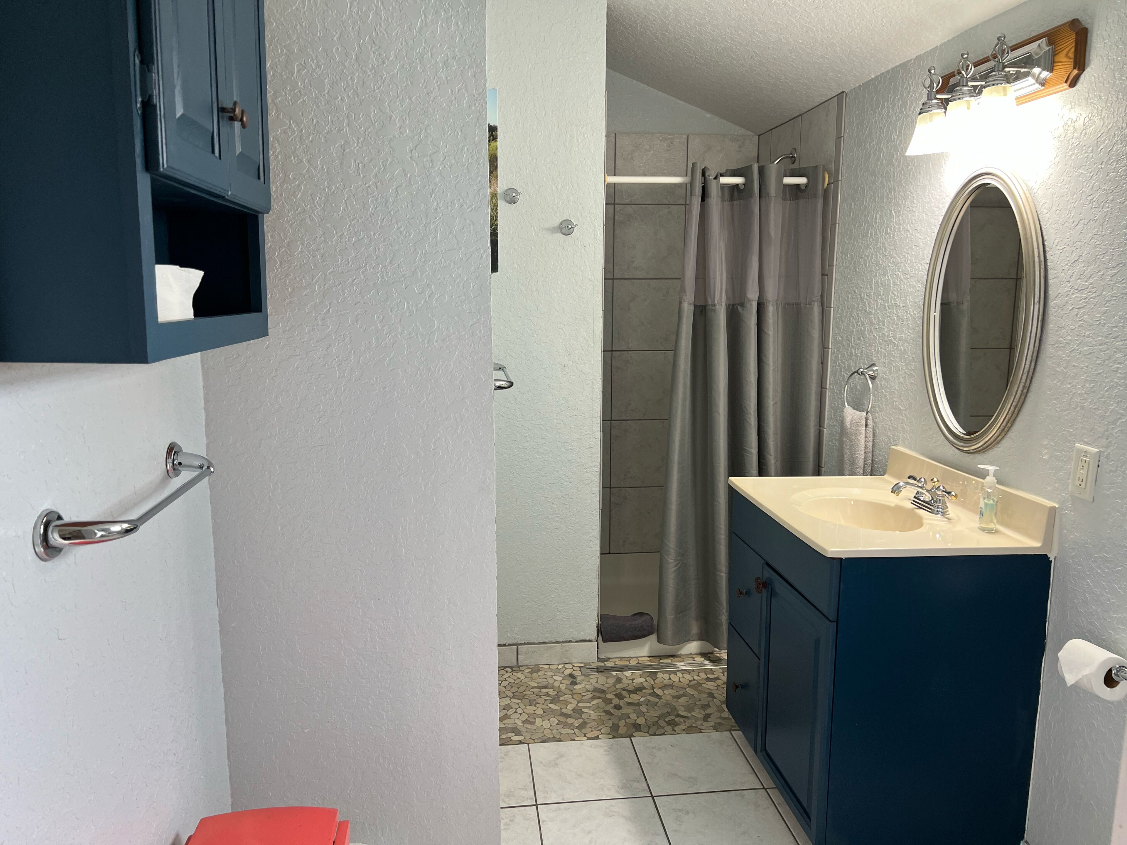 A bathroom with a shower, a sink with a mirror, and a towel rack.