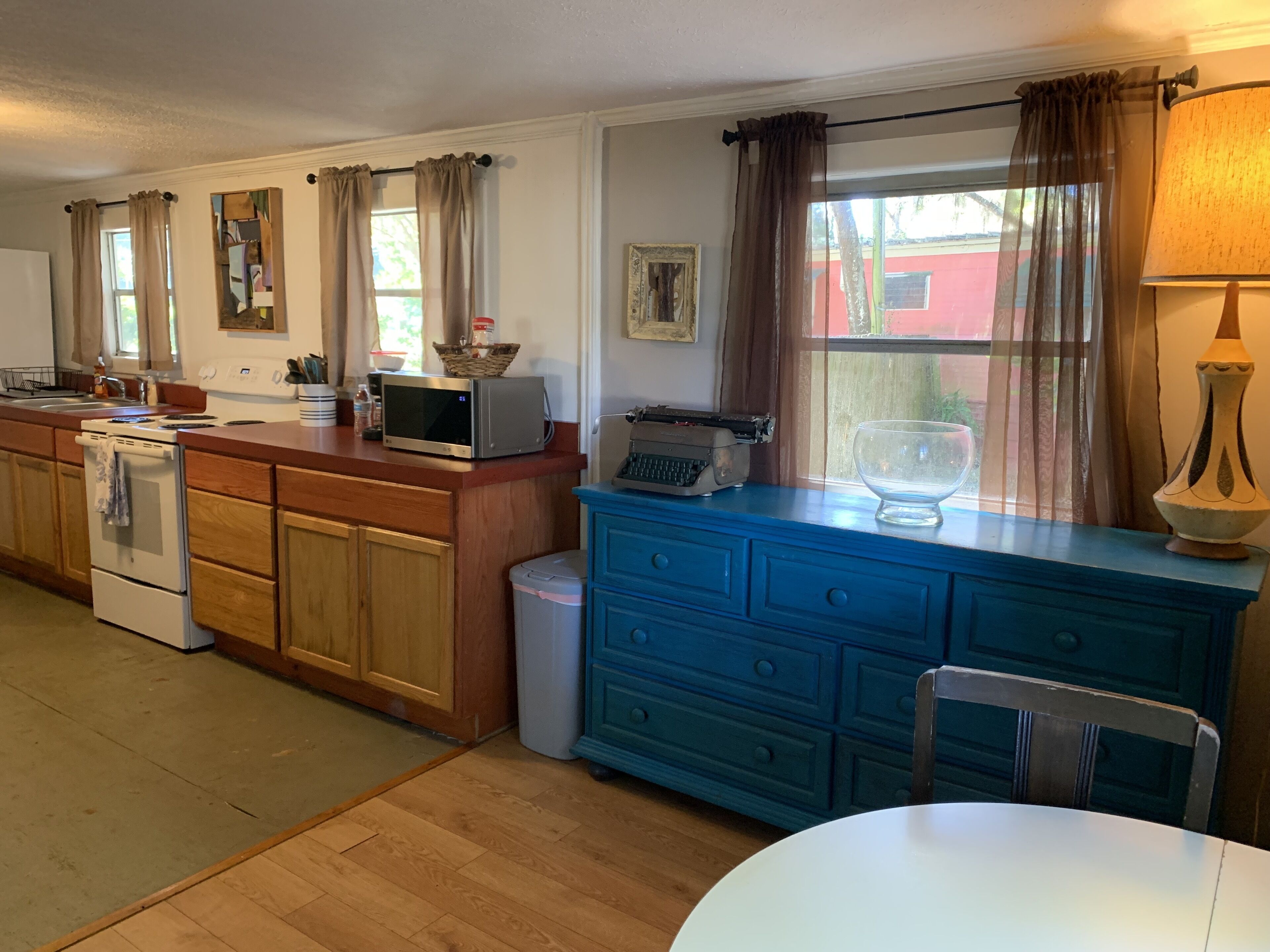 Una cocina con armarios de madera, un microondas, una estufa, un fregadero y un aparador azul.