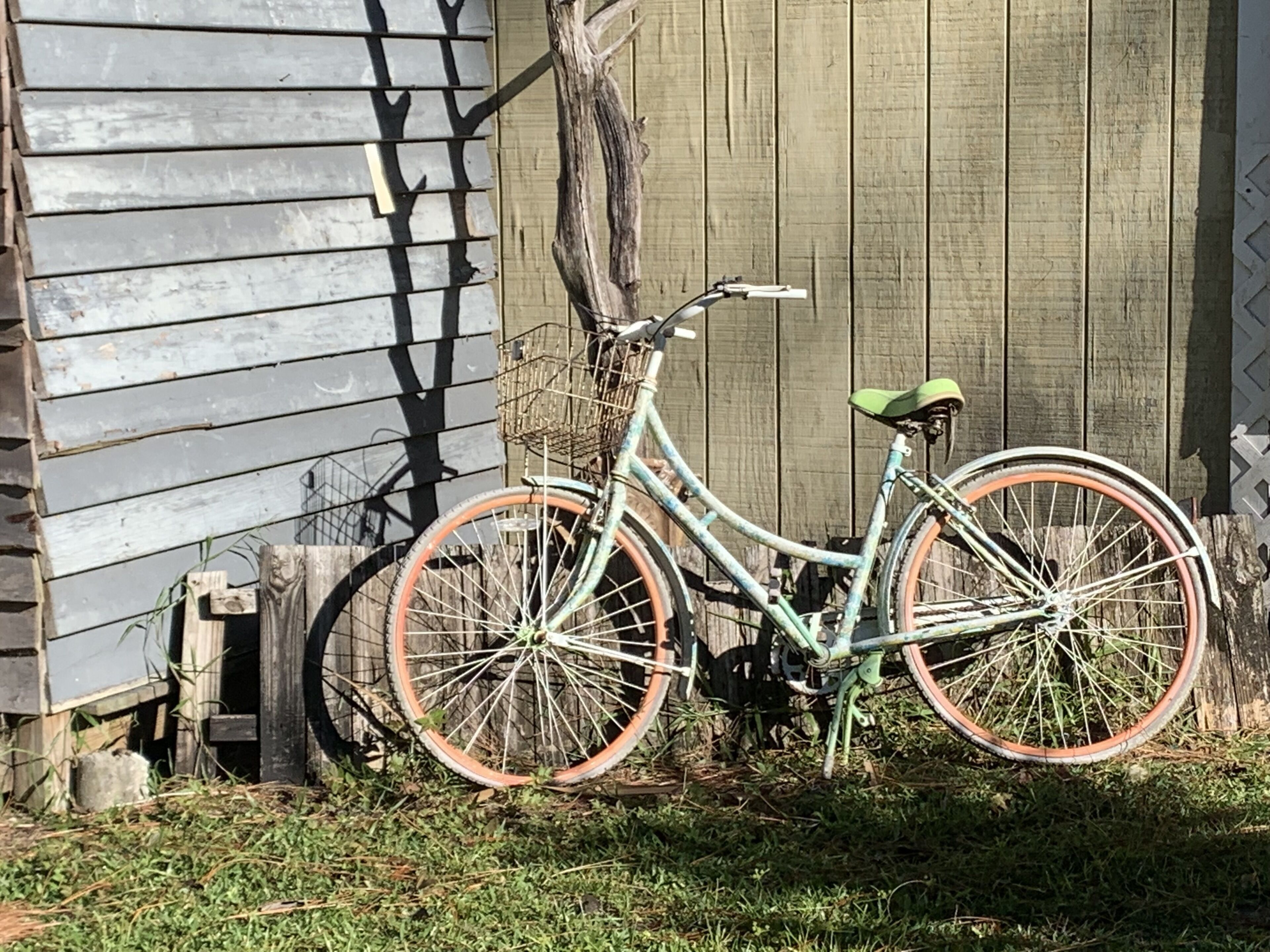 A bicycle parked against a wooden fence.