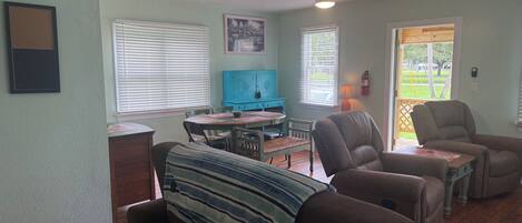 Un salon comprenant un canapé, deux fauteuils, une table basse et un meuble bleu.