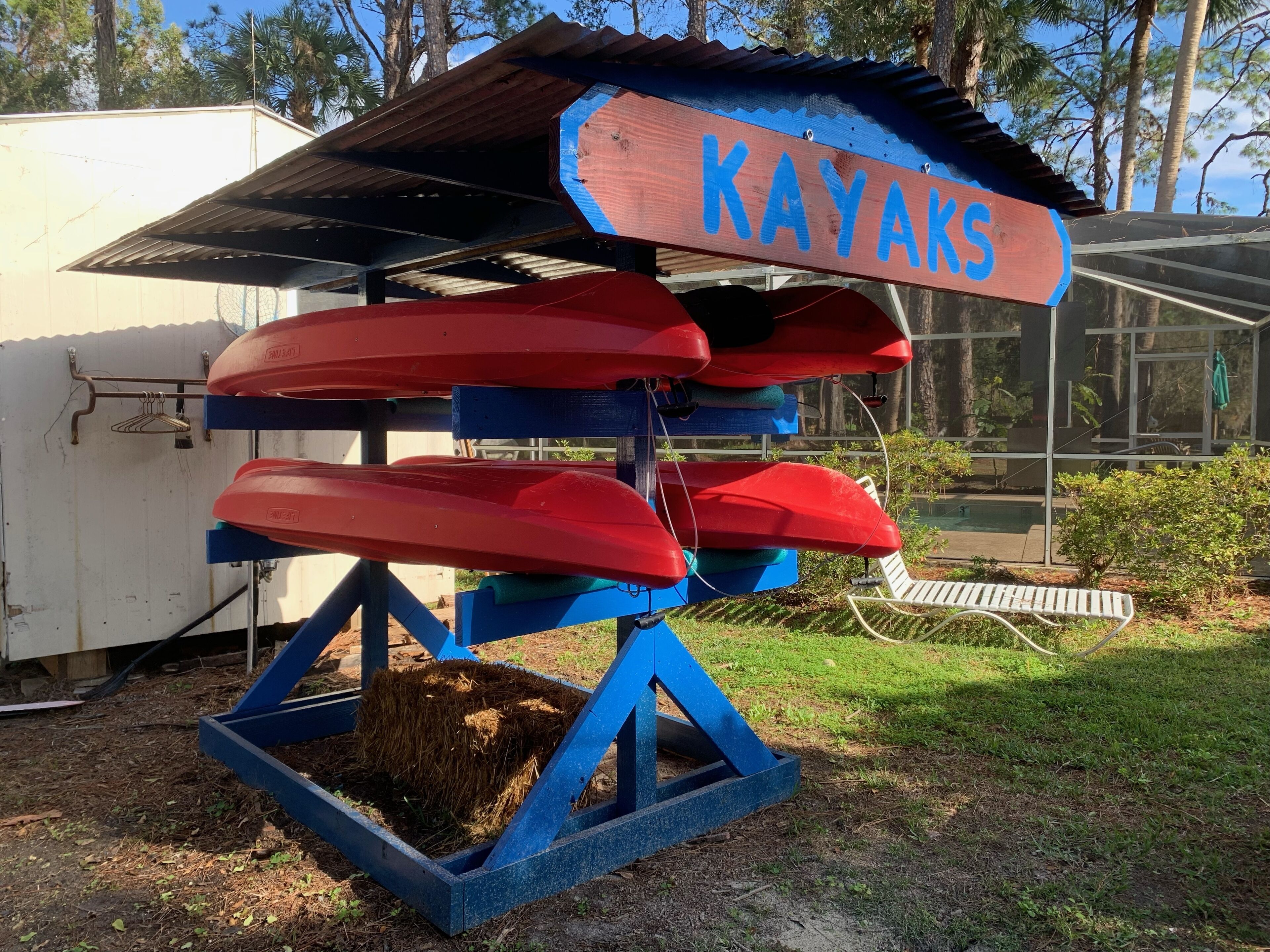 Katettu rakennelma, jossa on kyltti, jossa lukee ”KAYAKS”, ja sen alla on useita punaisia kajakkeja.