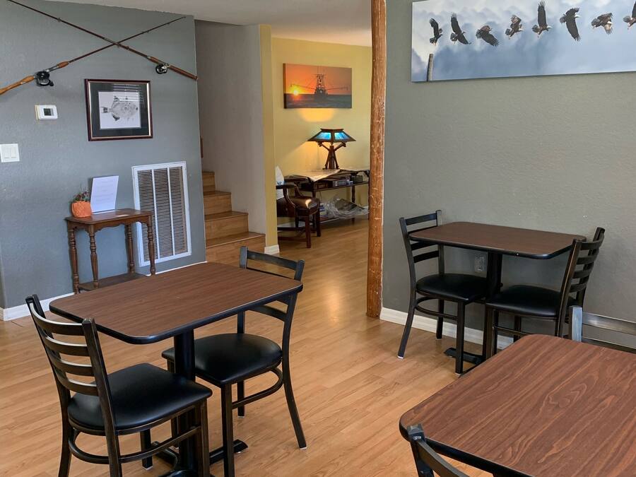 A dining area with wooden tables and chairs, a chandelier, and a painting of birds on the wall.