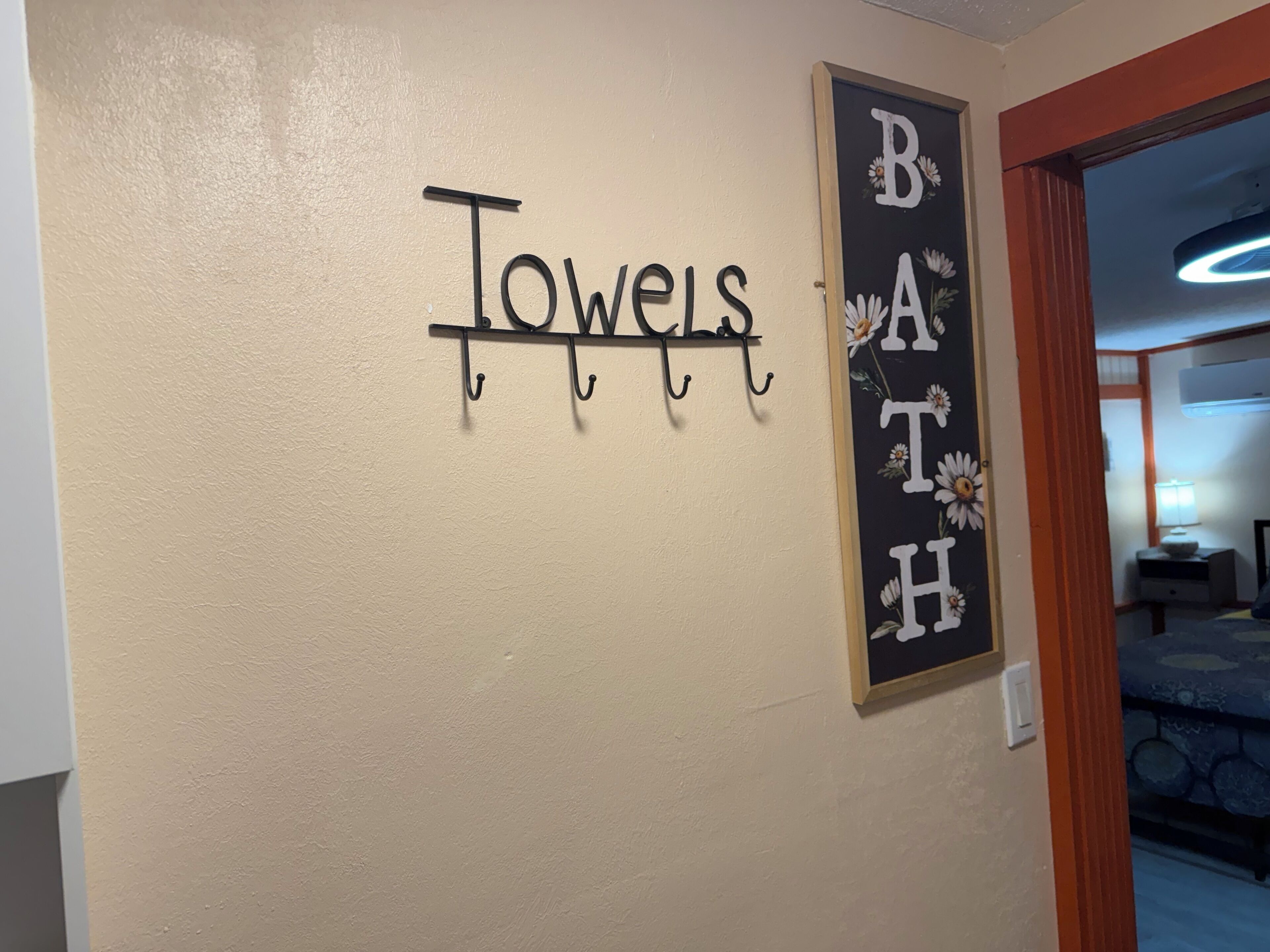 A wall with a towel rack and a sign that reads "Towels Bath".