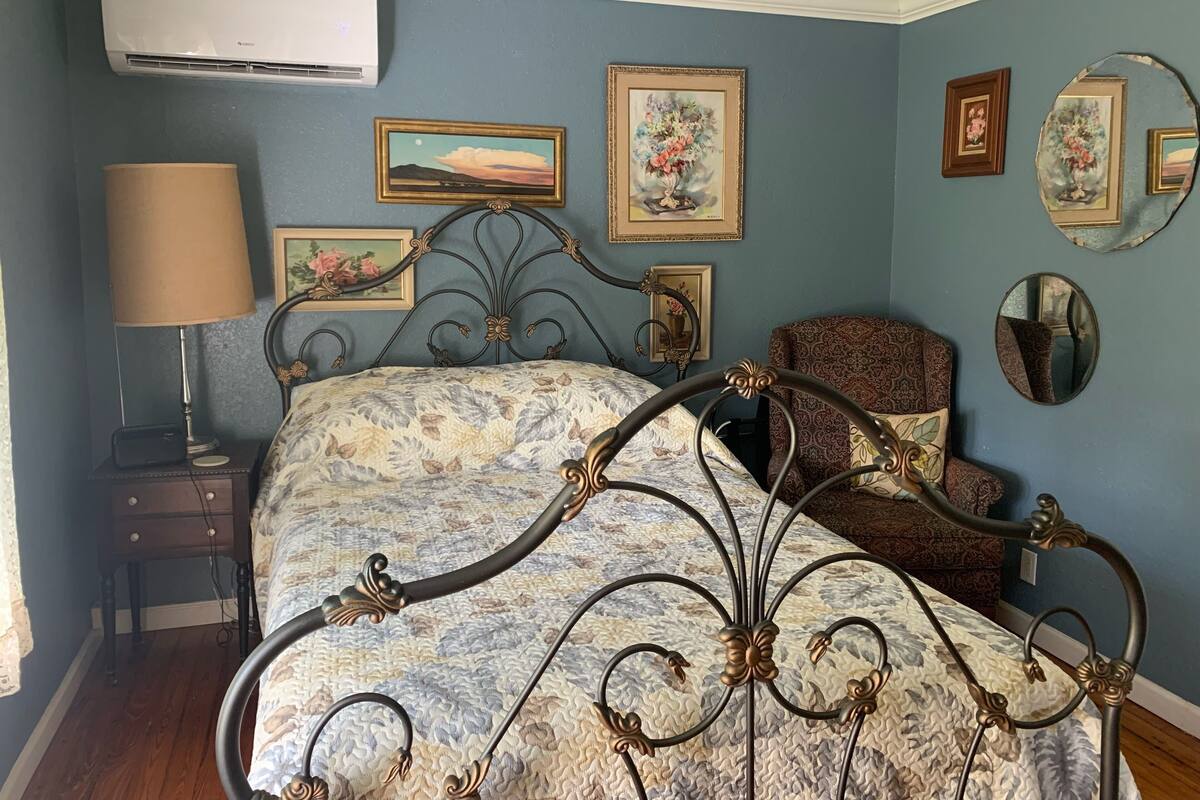 A bedroom with a bed, a bedside table, a lamp, and wall-mounted mirrors.