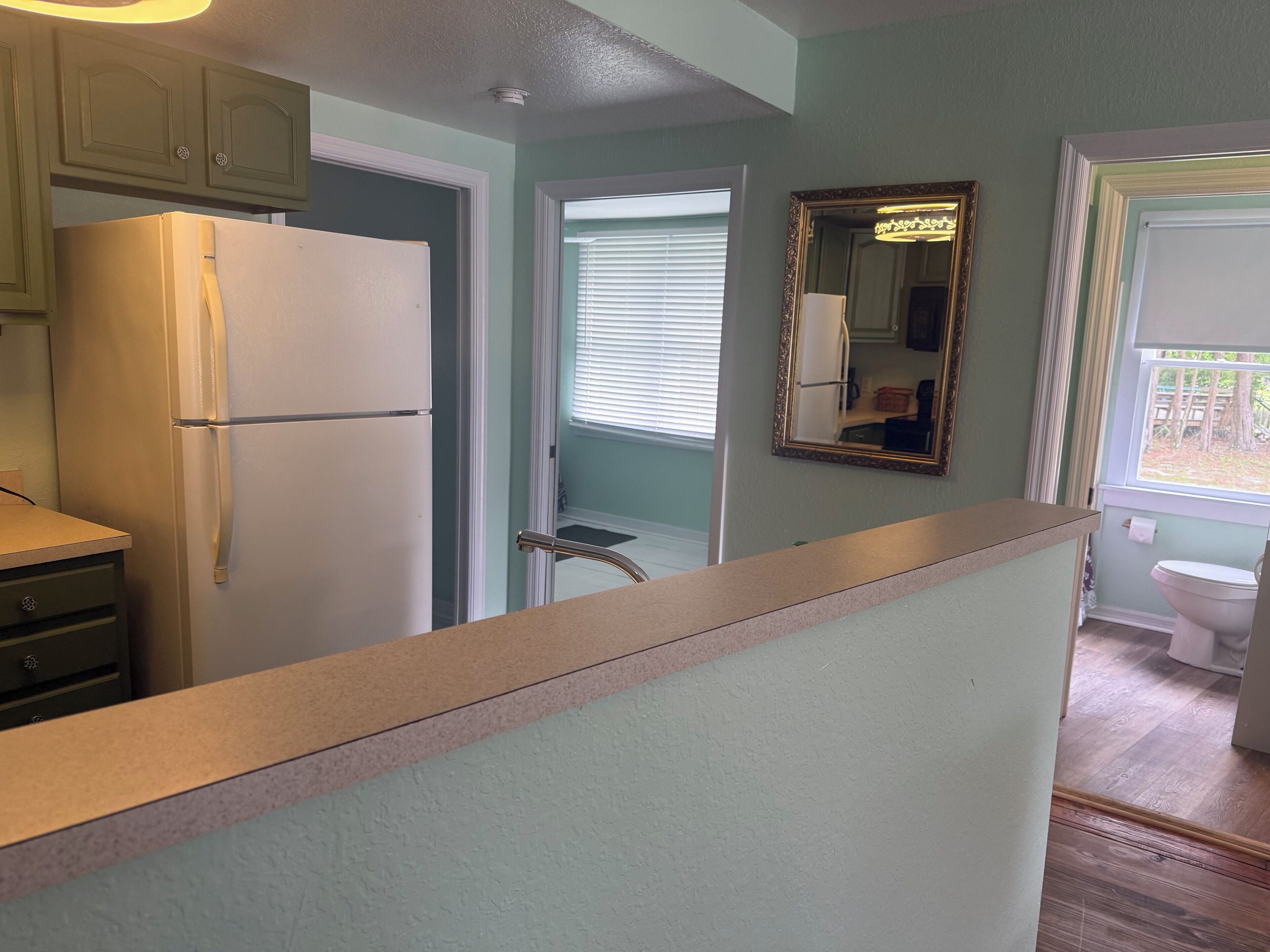 A kitchen with a refrigerator, cabinets, and a window.