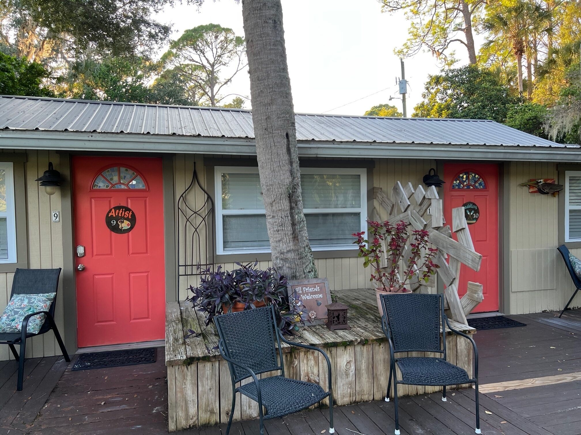 Un bâtiment avec une porte rouge portant l’inscription « Artiste 9 » et une pancarte accueillant tous les amis.