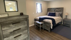 A bedroom with a bed, a dresser, a nightstand, a window, and a mirror. - Cozy Cottage, Quiet and Peaceful, Minutes from Lake Guntersville (Grant)