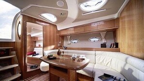 A compact, well-lit interior with a dining area, seating, and a small kitchenette. - Yacht "BAVARIA 37 SPORT "RIBELLE"" in Sardinia - with a sporty design (Olbia)