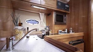 A compact kitchen with a stainless steel sink, a microwave, and a coffee maker. - Yacht "BAVARIA 37 SPORT "RIBELLE"" in Sardinia - with a sporty design (Olbia)