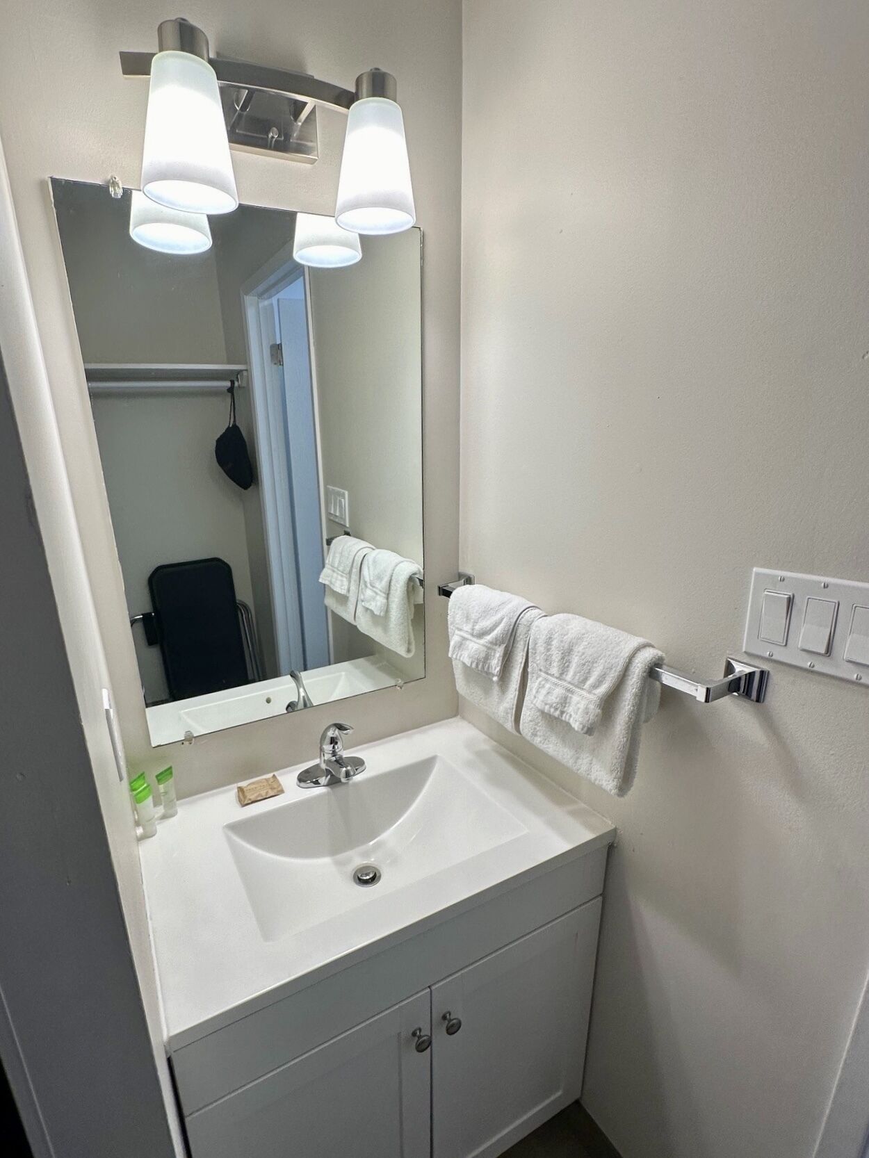 Un baño con un lavabo blanco, un espejo y dos luces en el techo.