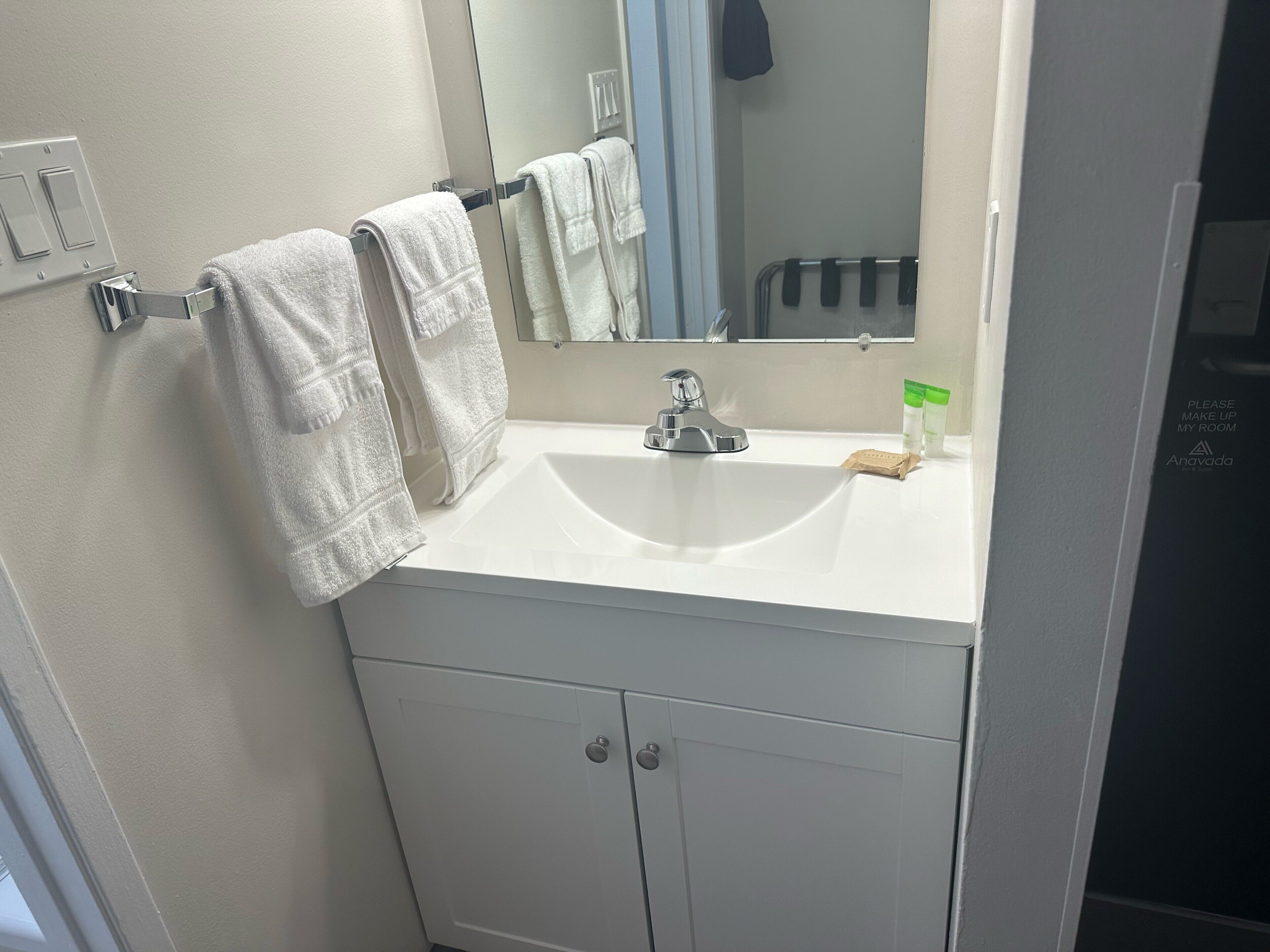 A bathroom with a white sink, a mirror, and two towels hanging on a towel rack.