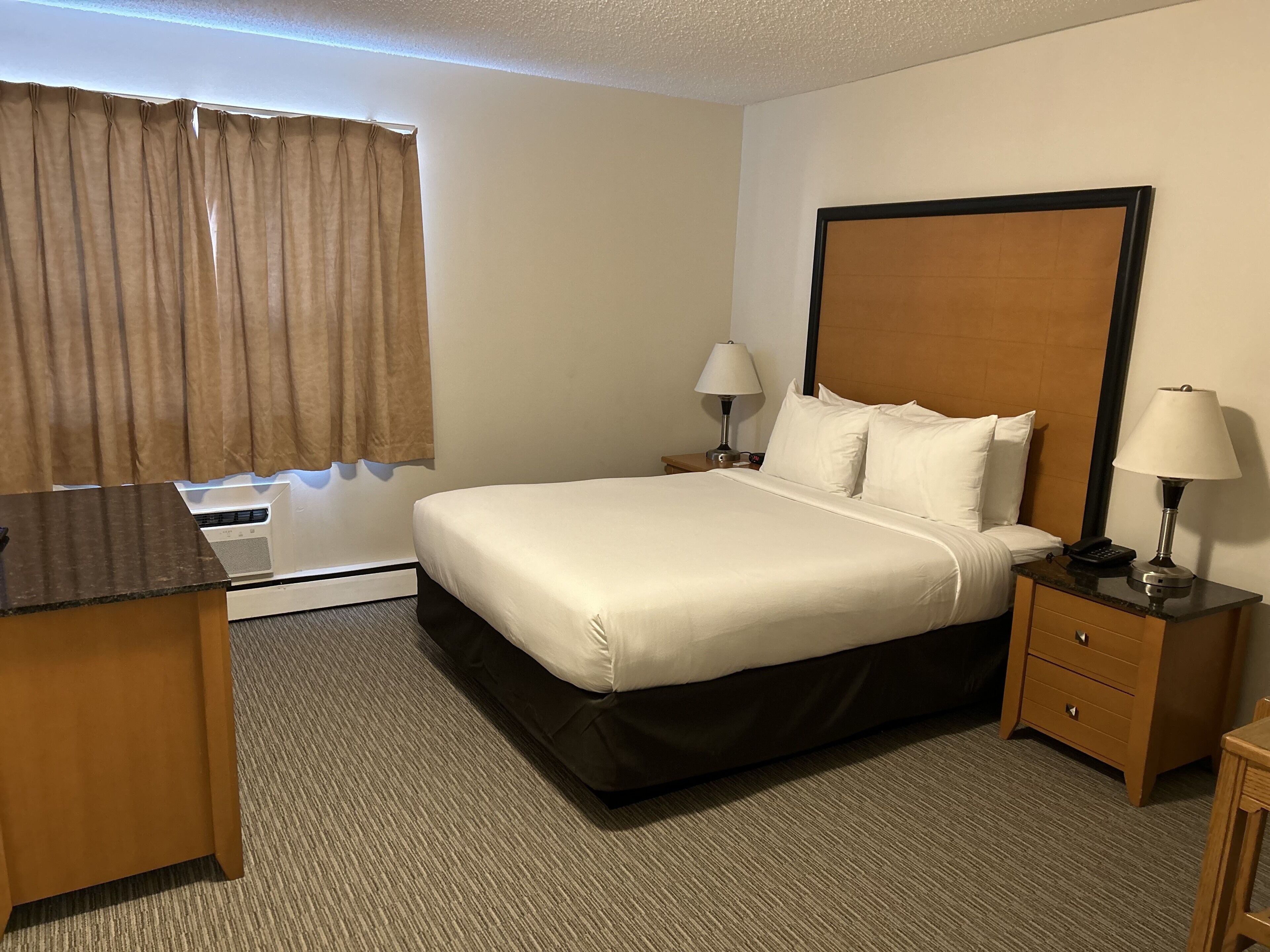 A hotel room with a bed, two bedside tables with lamps, a desk, and a chair.