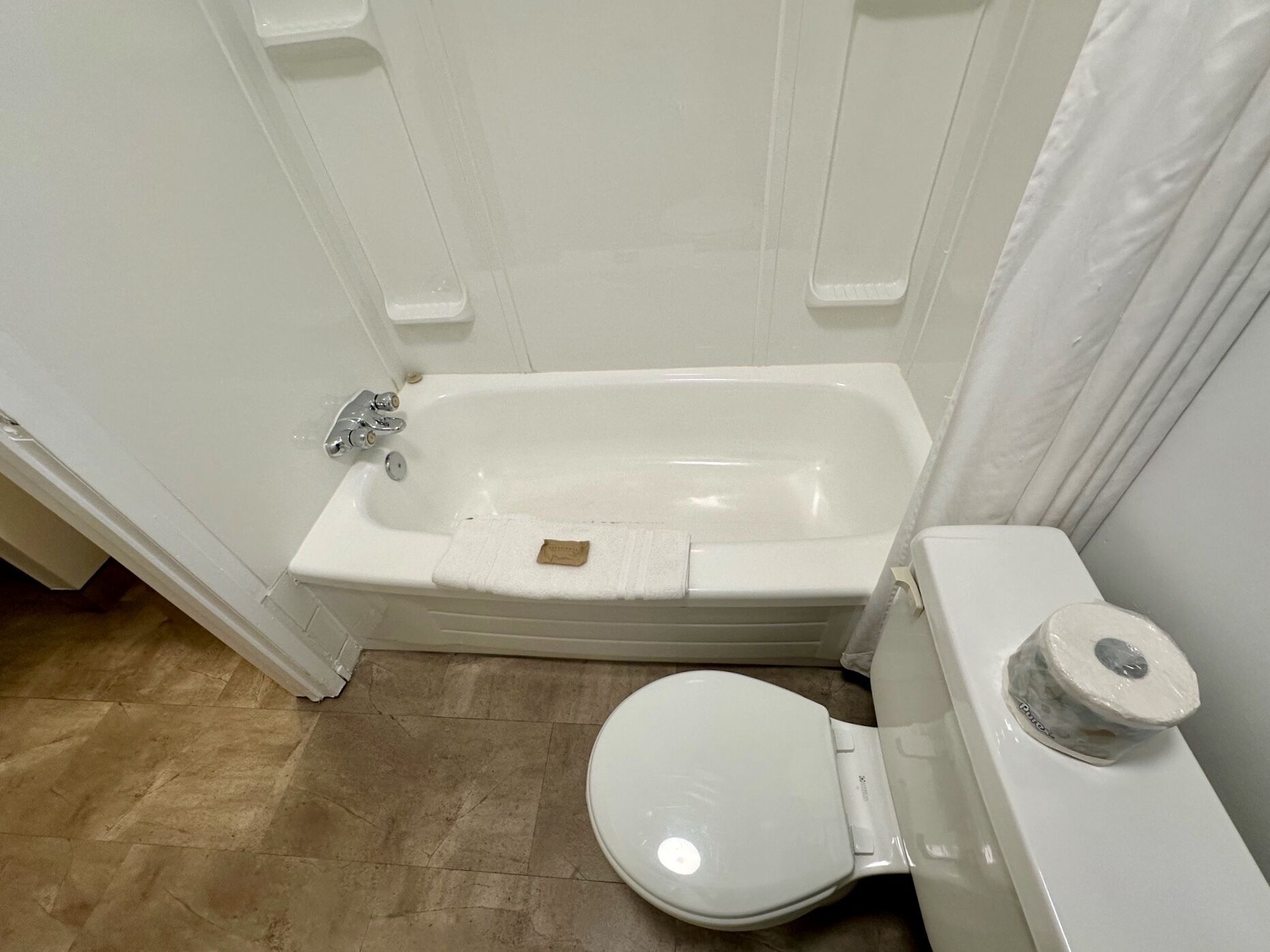 Un baño con una bañera blanca, un inodoro y un cortinón de ducha.