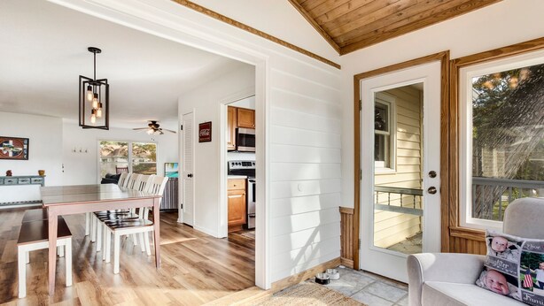 A spacious kitchen with wooden cabinets, a dining area with a large table and chairs, and a cozy living room with a sofa. - Sound Sanctuary: Canal Front w/ Dock, Dog-Friendly (Southern Shores)