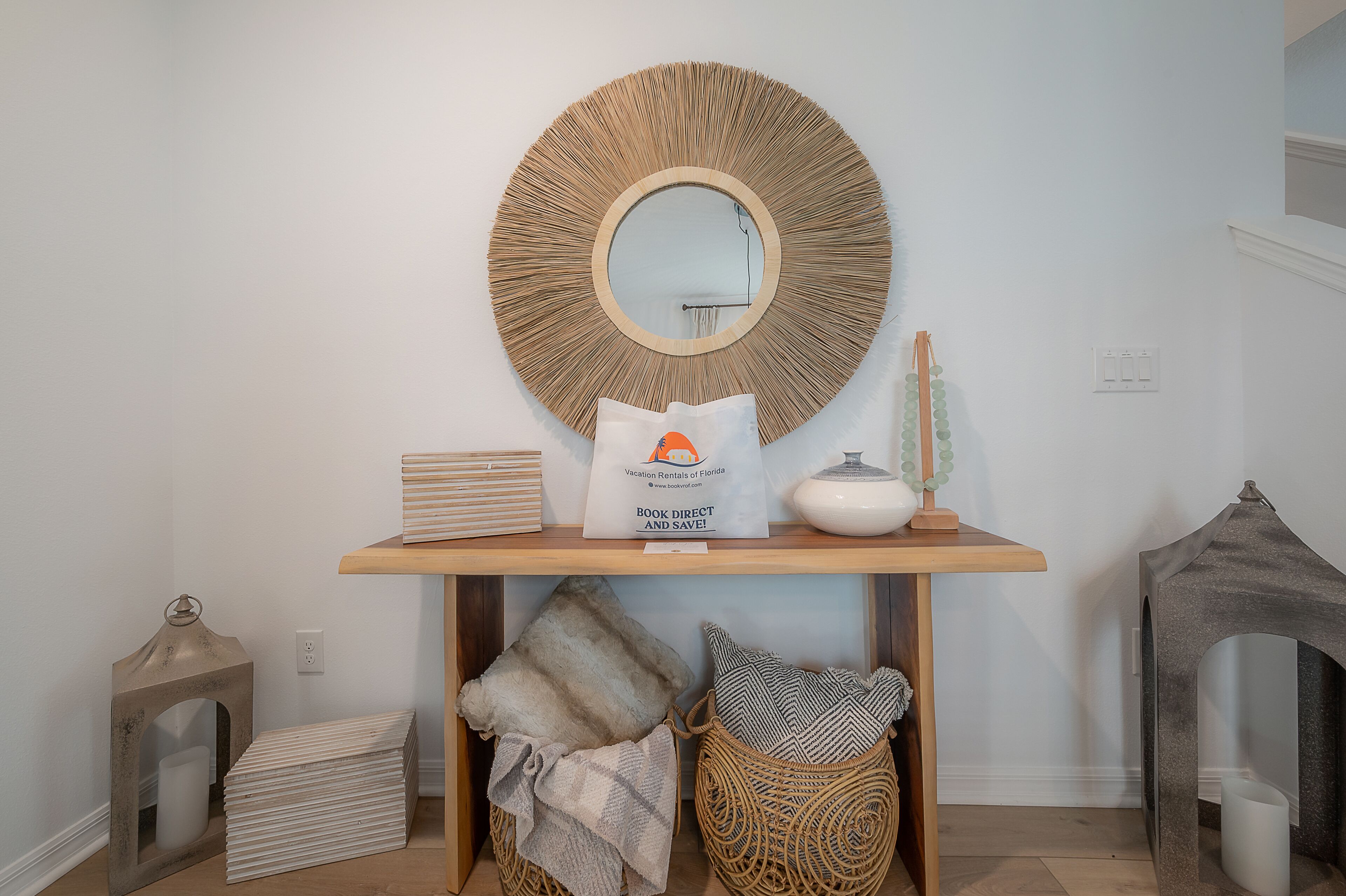 A wooden console table with a round mirror, a white bag, and decorative items.