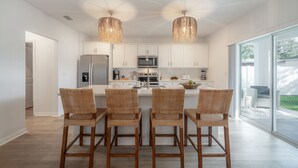 A modern kitchen with white cabinets, a central island with bar stools, and pendant lighting. - Tampa Oasis | 1 mi from Downtown Ybor City (Tampa)