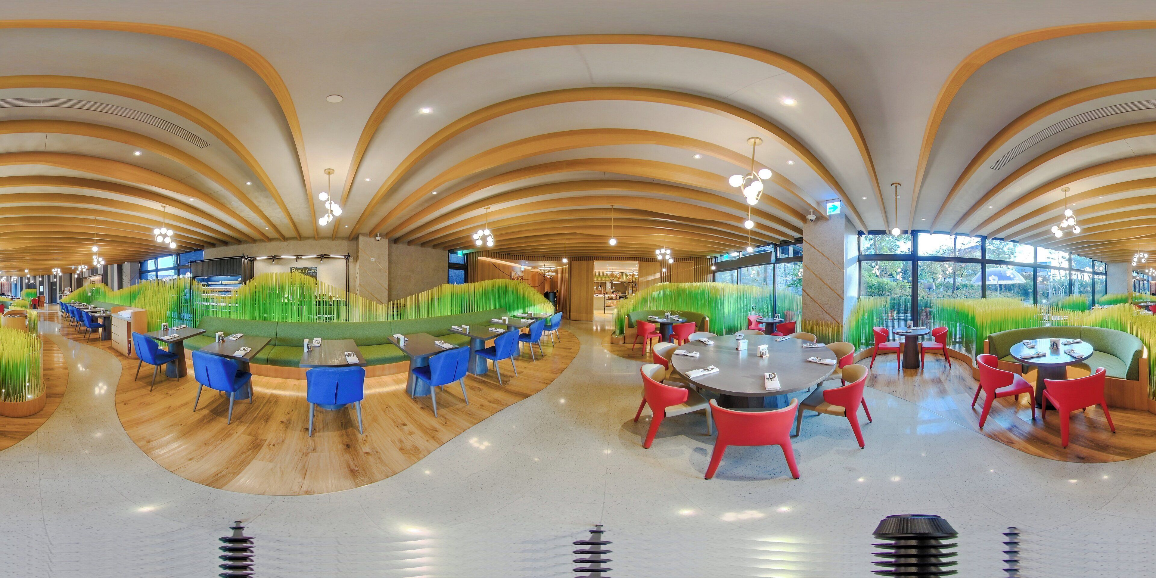 A modern restaurant with curved wooden ceilings, green seating areas, and a variety of table and chair arrangements.