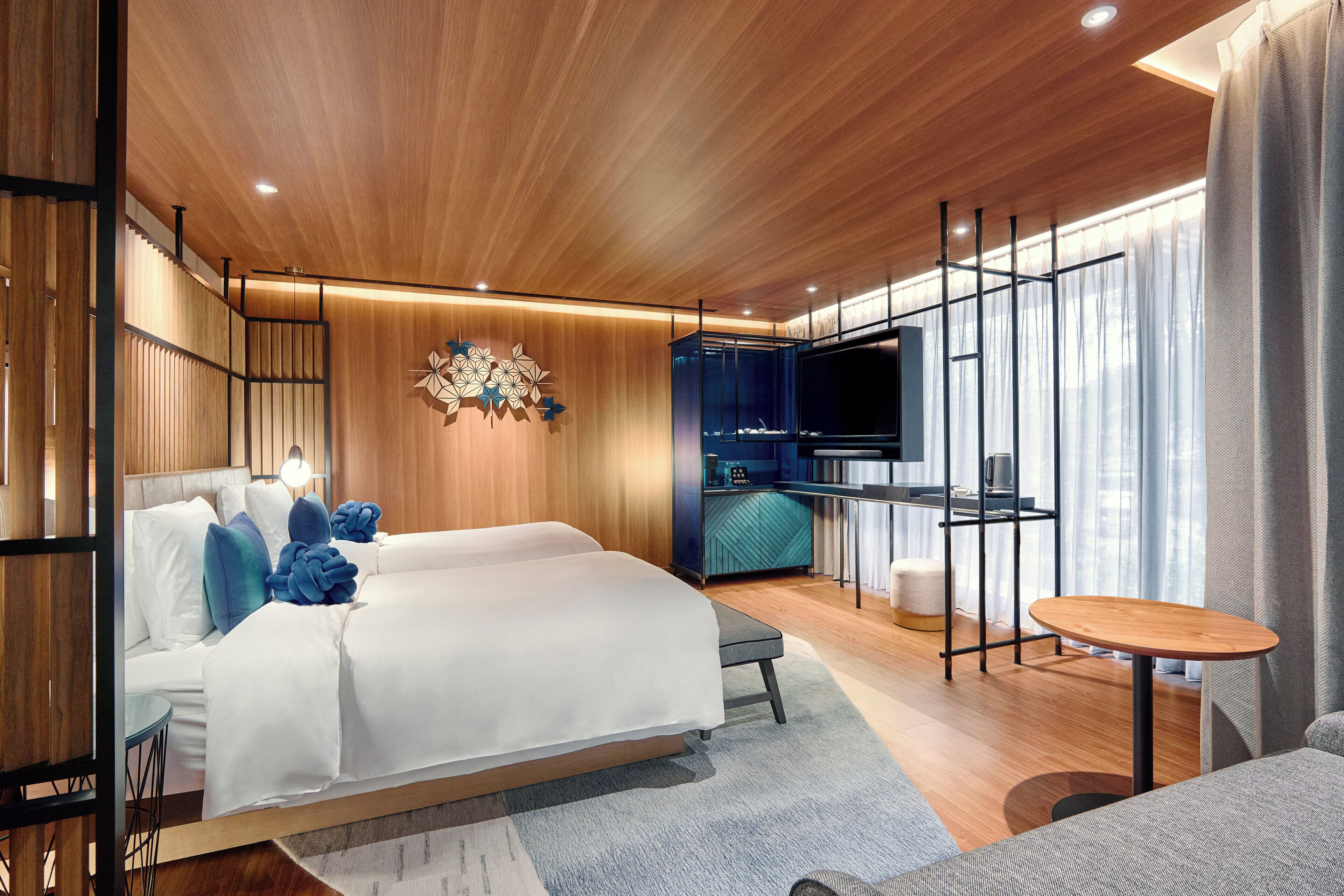 Una habitación de hotel moderna con una cama grande, un escritorio pequeño, un televisor y vistas a la ciudad.