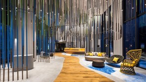 Een moderne lobby met een houten vloer, een receptiebalie en zitgedeeltes.