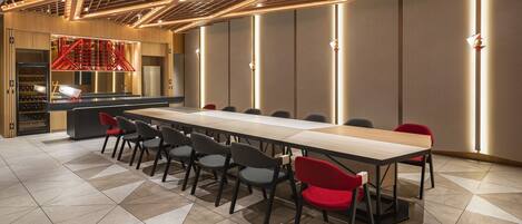 Une salle de conférence moderne, dotée d’une longue table, de plusieurs chaises et d’un meuble à vin.