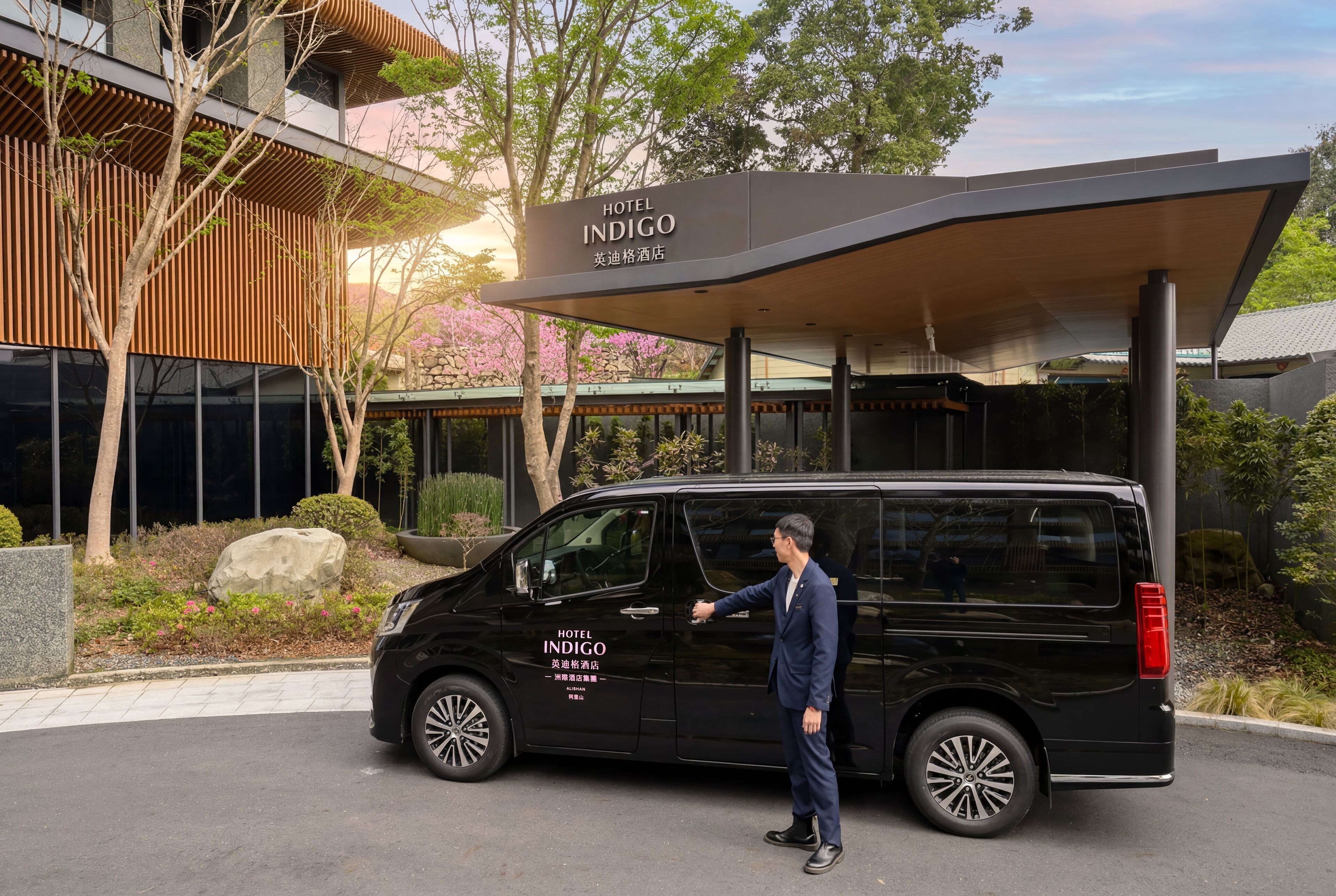 En sort varevogn parkeret foran en bygning med et skilt, der siger 'HOTEL INDIGO'.