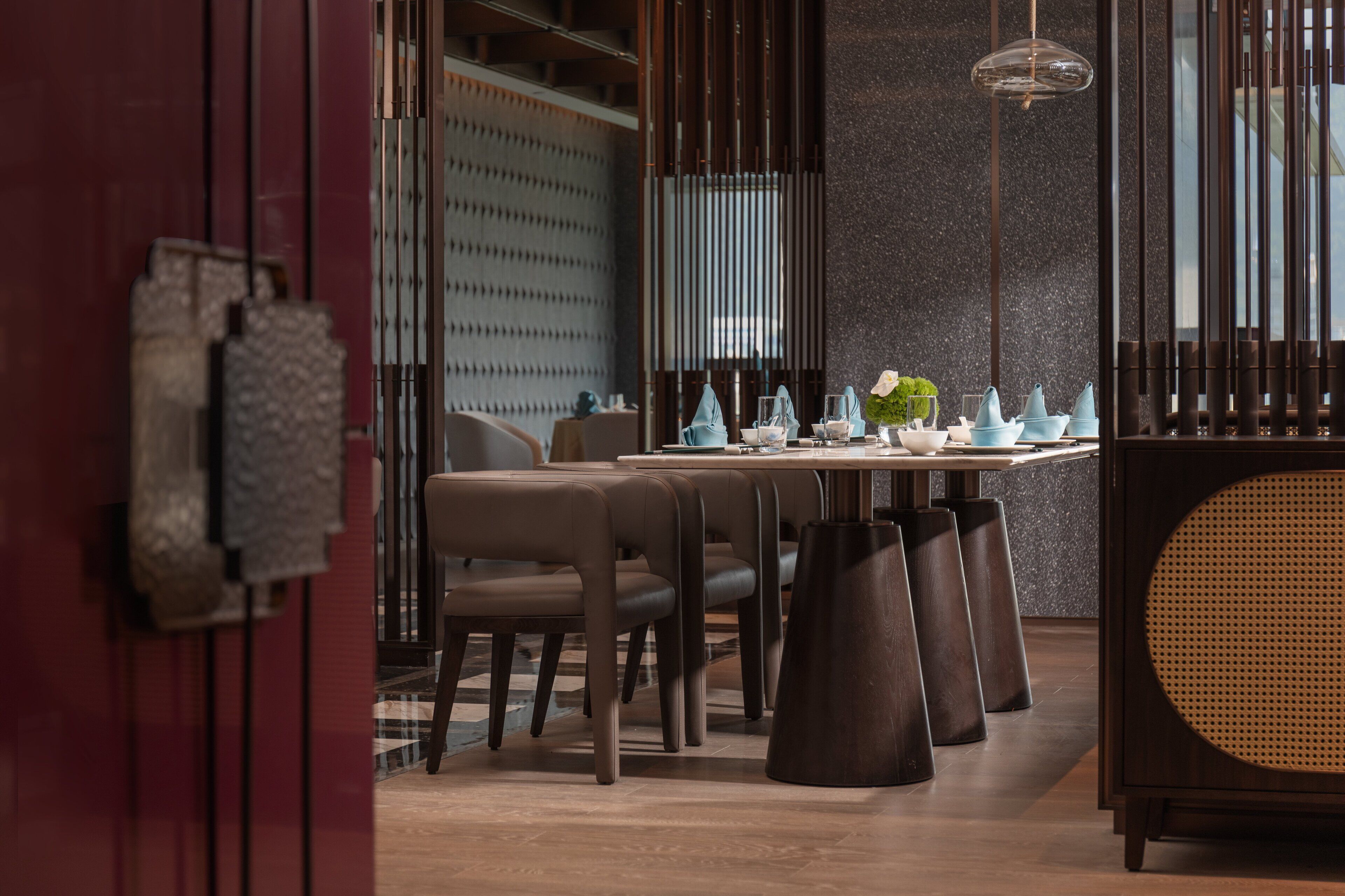 A modern dining area with a wooden table, chairs, and a decorative plant.