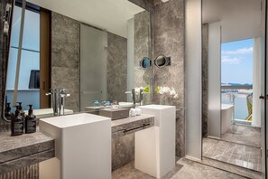 Une salle de bain moderne avec deux lavabos, un grand miroir et une vue sur un plan d’eau.