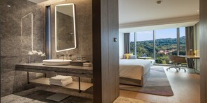 A modern hotel room with a large bed, a bathroom with a vanity, and a view of the landscape. - Crowne Plaza Ya an by IHG (Ya'an)