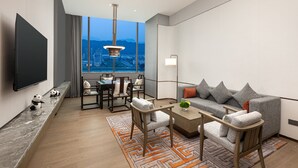 Una sala de estar moderna con un televisor grande, zona de estar y vistas a un paisaje urbano.