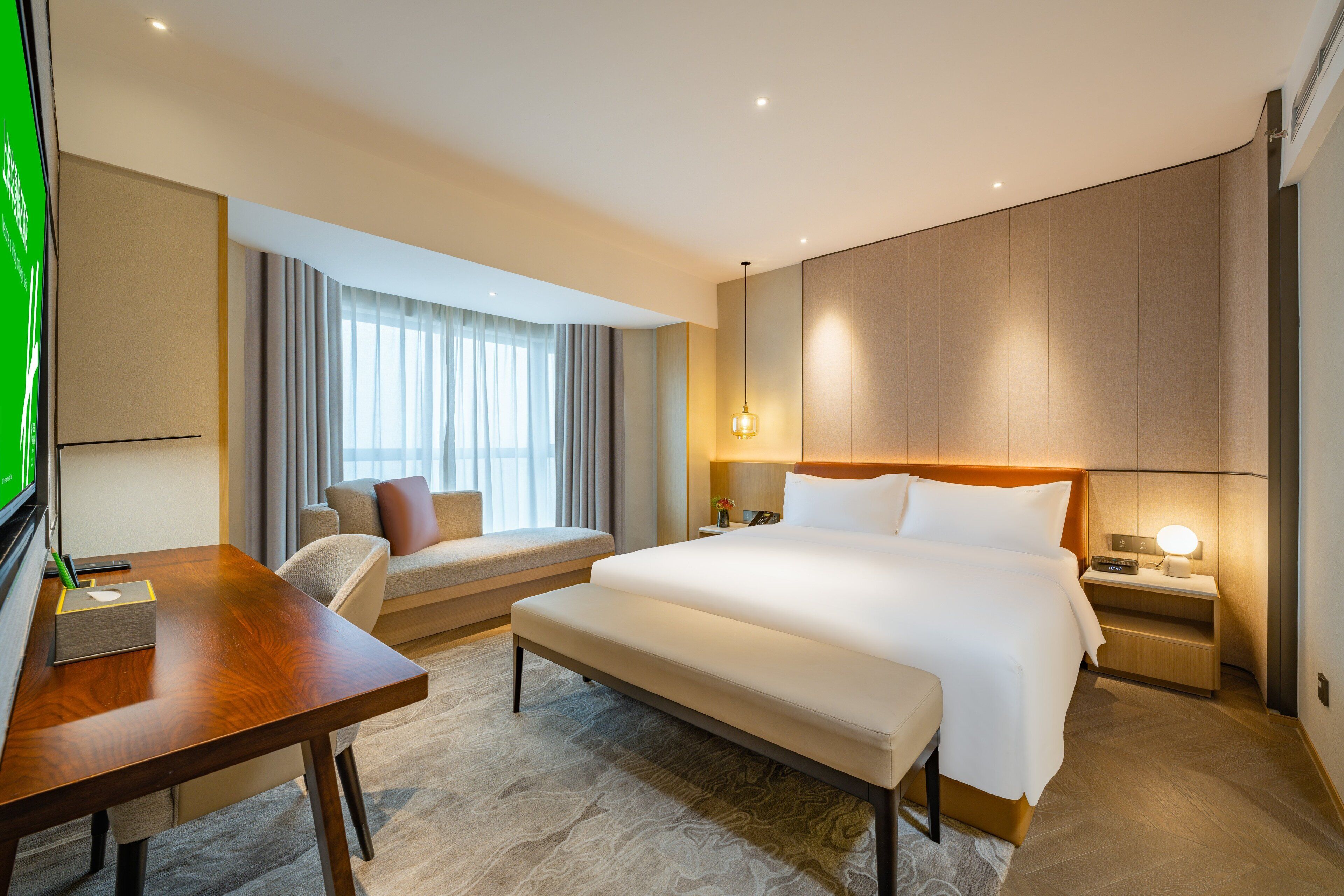A modern hotel room with a large bed, a desk, a comfortable sofa, and a TV.