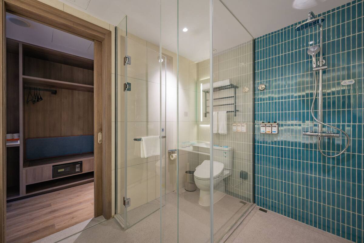 A modern bathroom with a glass-enclosed shower, a toilet, and a sink.