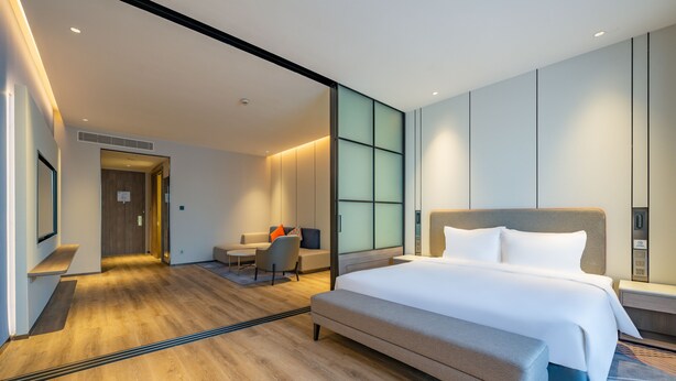 A modern hotel room with a large bed, a desk, and a seating area. - Holiday Inn Express Suzhou Luzhi by IHG (Suzhou)