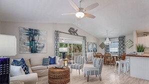 A spacious living area with a sofa, chairs, a coffee table, and a dining table. - On Point: Across Street from Bean Point Beach, Outdoor Games & Pool by Anna Maria Life (Anna Maria)